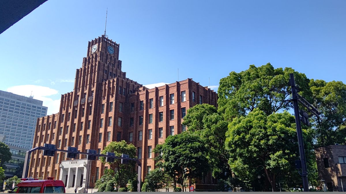 時計塔のあるれんが色の建物の手前に、こんもりと茂った公園の木々
