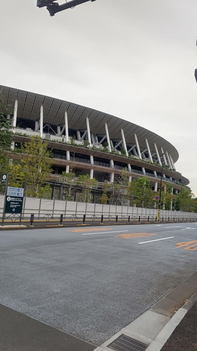 道路の向こうに見える国立競技場。外周の階ごとに木の軒庇が重なり、上に大屋根がかかる